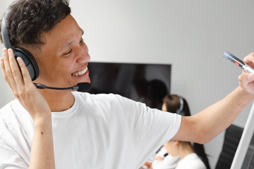 Smiling call center agent wearing headset and writing on whiteboard in office setting.